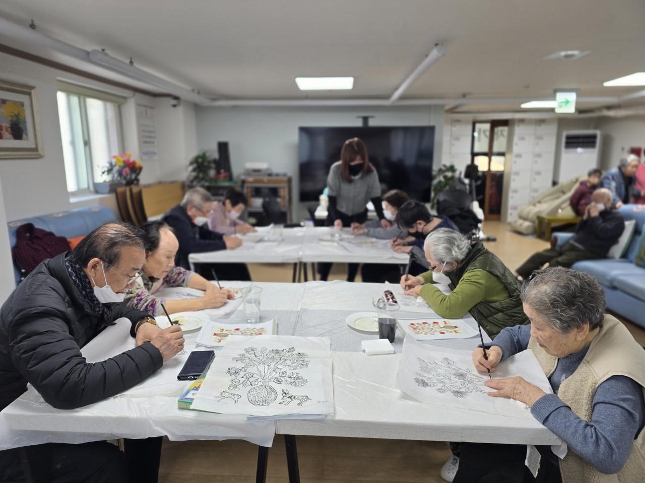 At a community daycare center in Yeoksam, southern Seoul, elderly participants engage in a minhwa (Korean folk art) painting program. (Yeoksam Home Elderly Daycare Center)