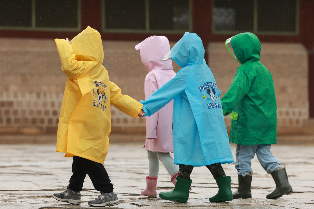 Children in rain coats walk together while holding hands through Gyeongbokgung in Jongno-gu, central Seoul on May 9. (Yonhap)