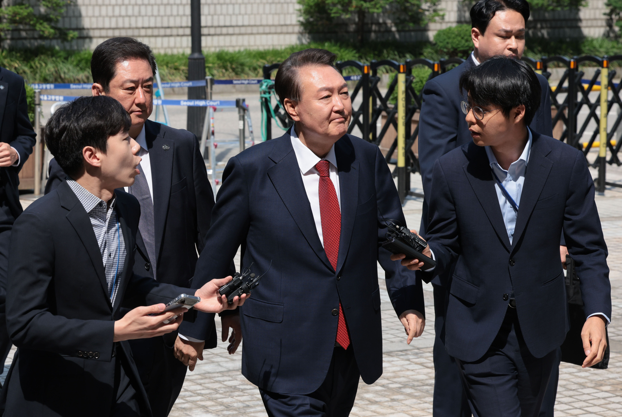 Former President Yoon Suk Yeol looks at his supporters as he appears at the Seoul Central District Court in the capital on Monday to attend the fifth hearing of a trial over insurrection charges in connection with his declaration of martial law. (Yonhap)