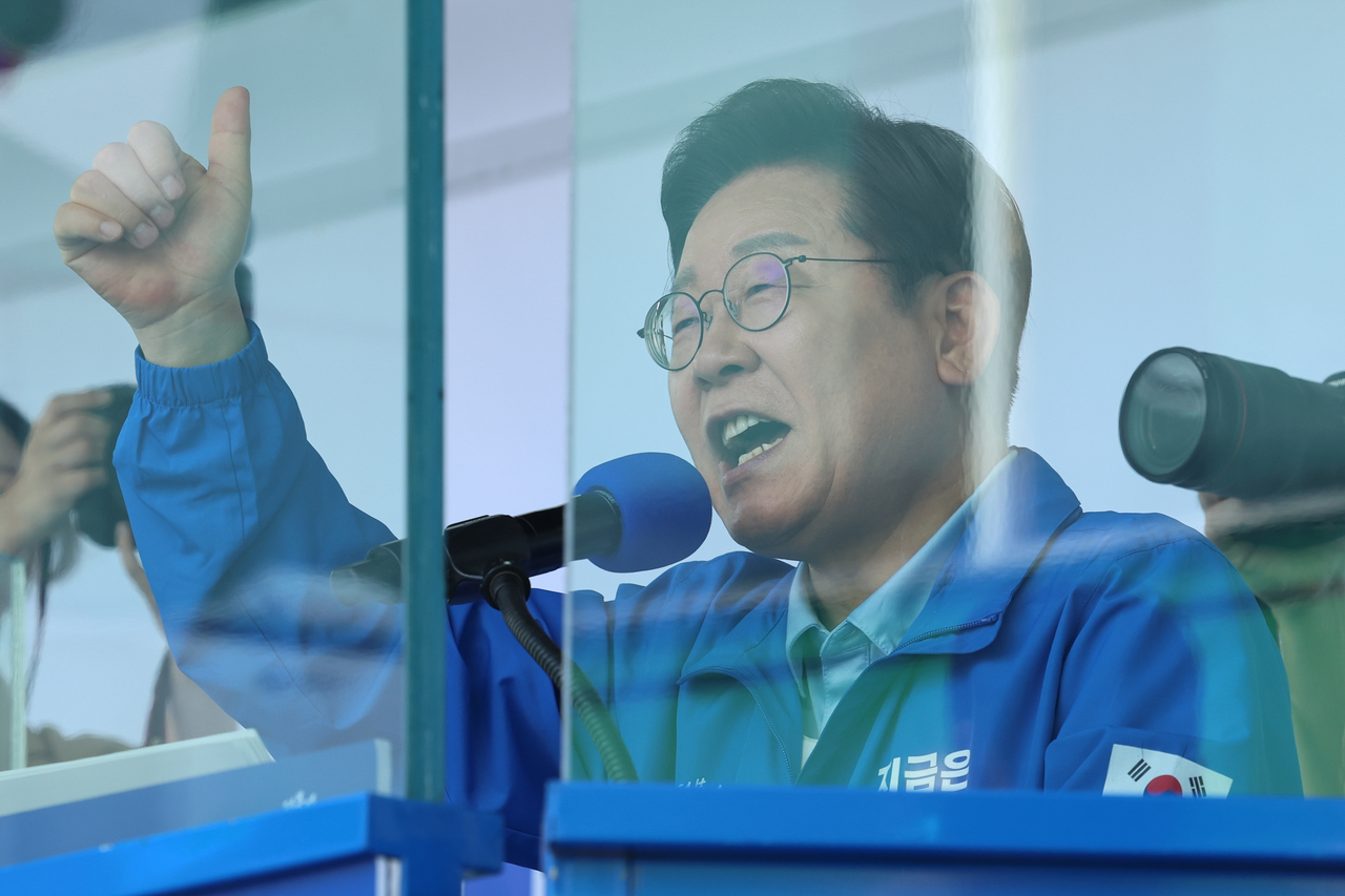 Democratic Party of Korea presidential candidate Rep. Lee Jae-myung speaks to a crowd of supporters from behind a wall of bulletproof glass at a rally in Suwon, Gyeonggi Province, Monday. Yonhap