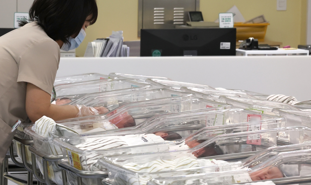 Newborns rest in bassinets as a nurse provides care at Ain Hospital in Incheon in February this year. (Newsis)