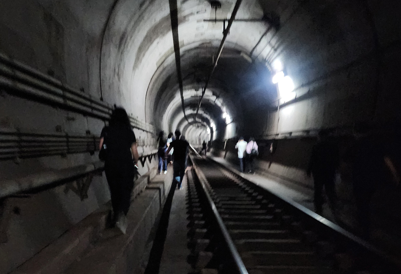 Passengers evacuate through a tunnel after a suspected arson fire breaks out on a Seoul subway train between Yeouinaru and Mapo stations around 8:47 a.m. on Friday. (Yonhap)