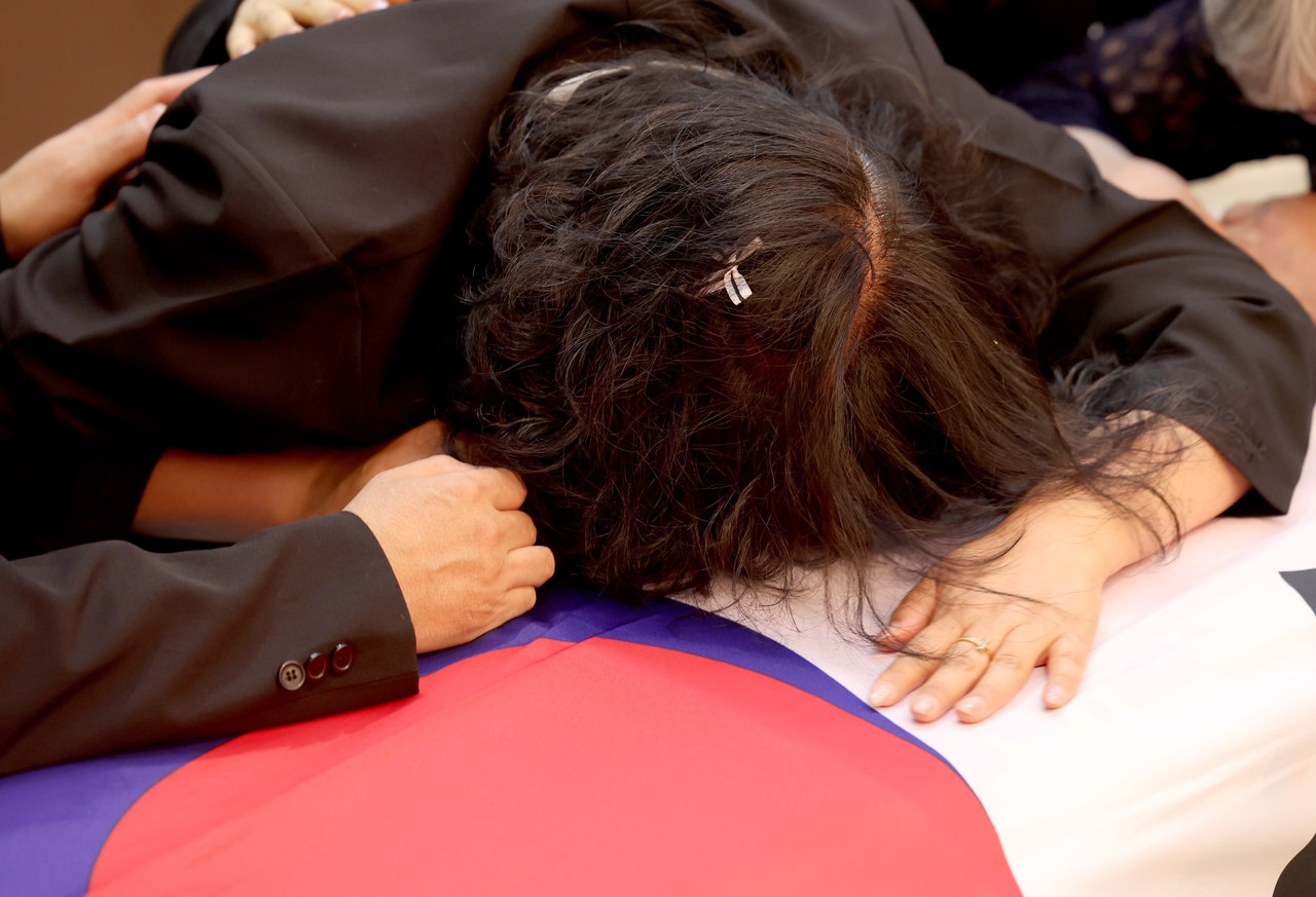 A grieving family member collapses in sorrow over a flag-draped casket during Sunday’s Navy funeral for P-3CK crash victims in Pohang, North Gyeongsang Province. (Yonhap)