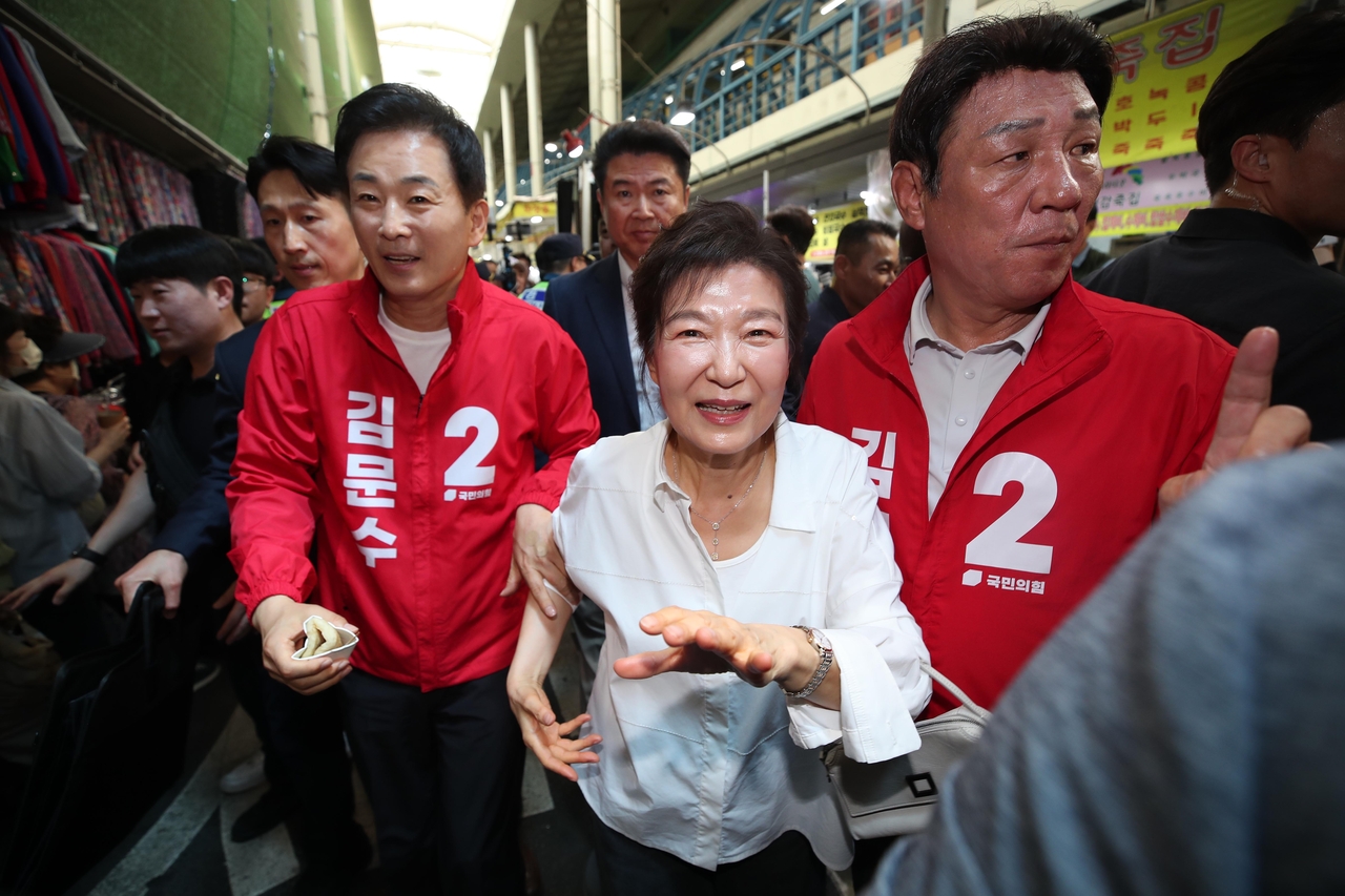 Former President Park Geun-hye (center) greets supporters at a local market in Daegu, Saturday, accompanied by Reps. Yoo Yeong-ha (left) and Kang Dae-sik. (Yonhap)