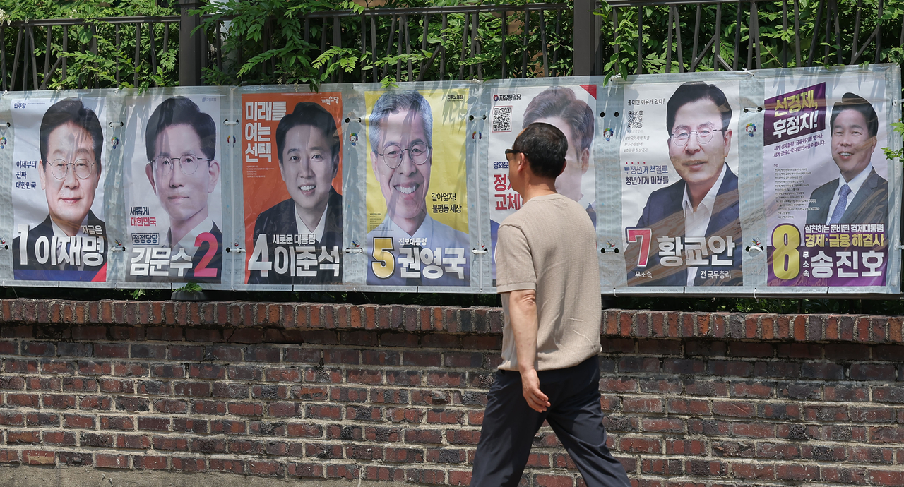 A pedestrian walks in front of a display of presidential campaign posters at Jongno-gu, central Seoul, Sunday. (Yonhap)