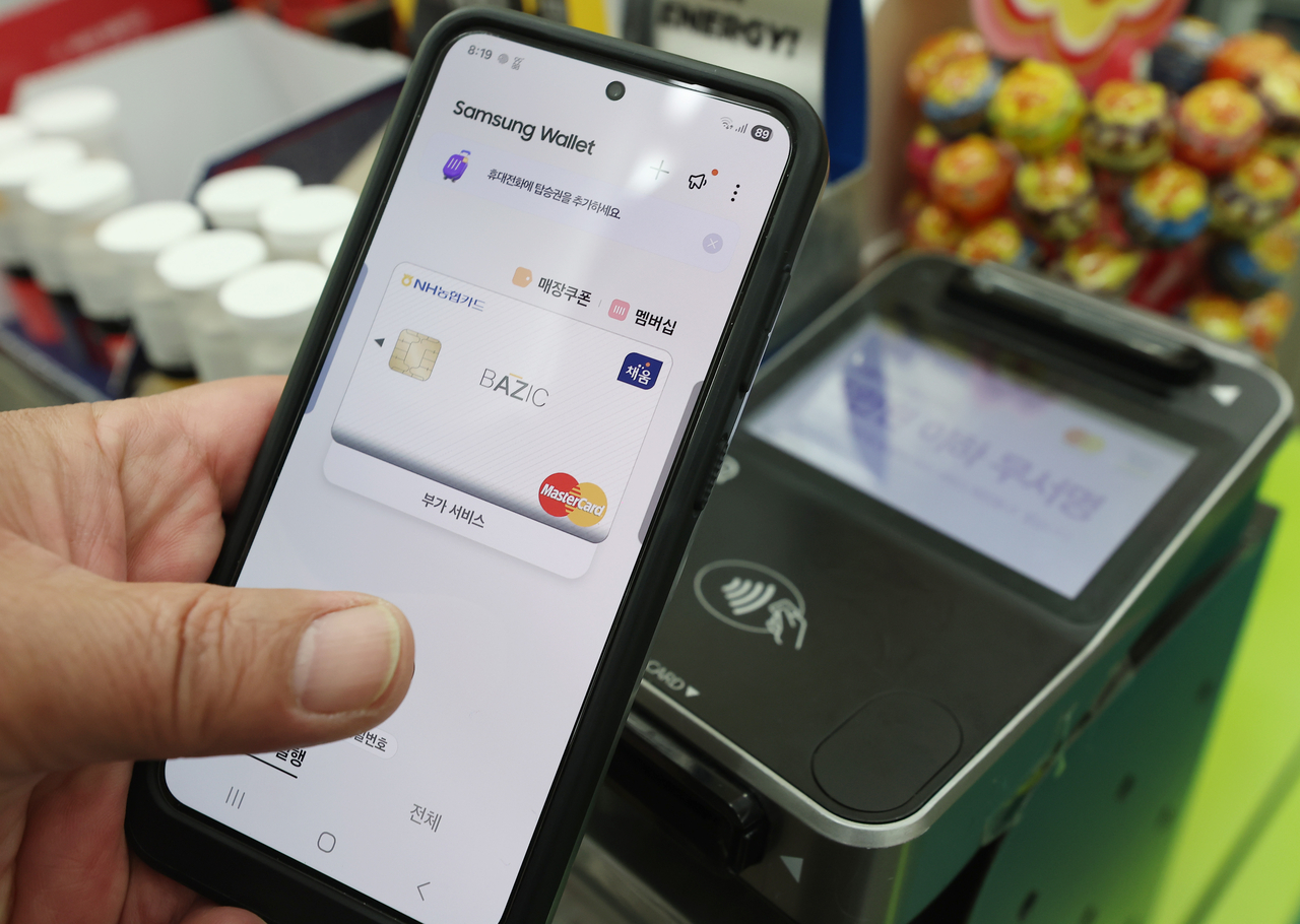A Samsung Pay user attempts to log in using fingerprint recognition at a payment terminal in a convenience store in Seoul on Monday. (Yonhap)