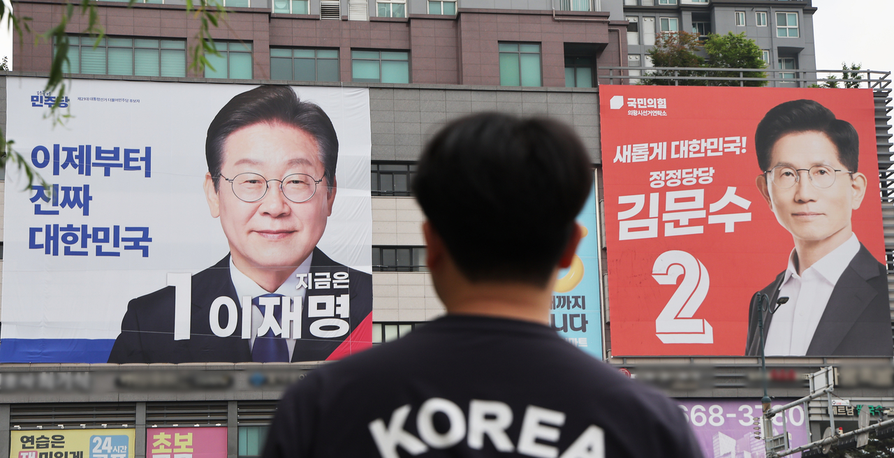 Large banners of Democratic Party candidate Lee Jae-myung (left) and People Power Party candidate Kim Moon-soo are displayed on a building in Uiwang City, Gyeonggi Province, on Monday, one day before the 21st presidential election. (Yonhap)
