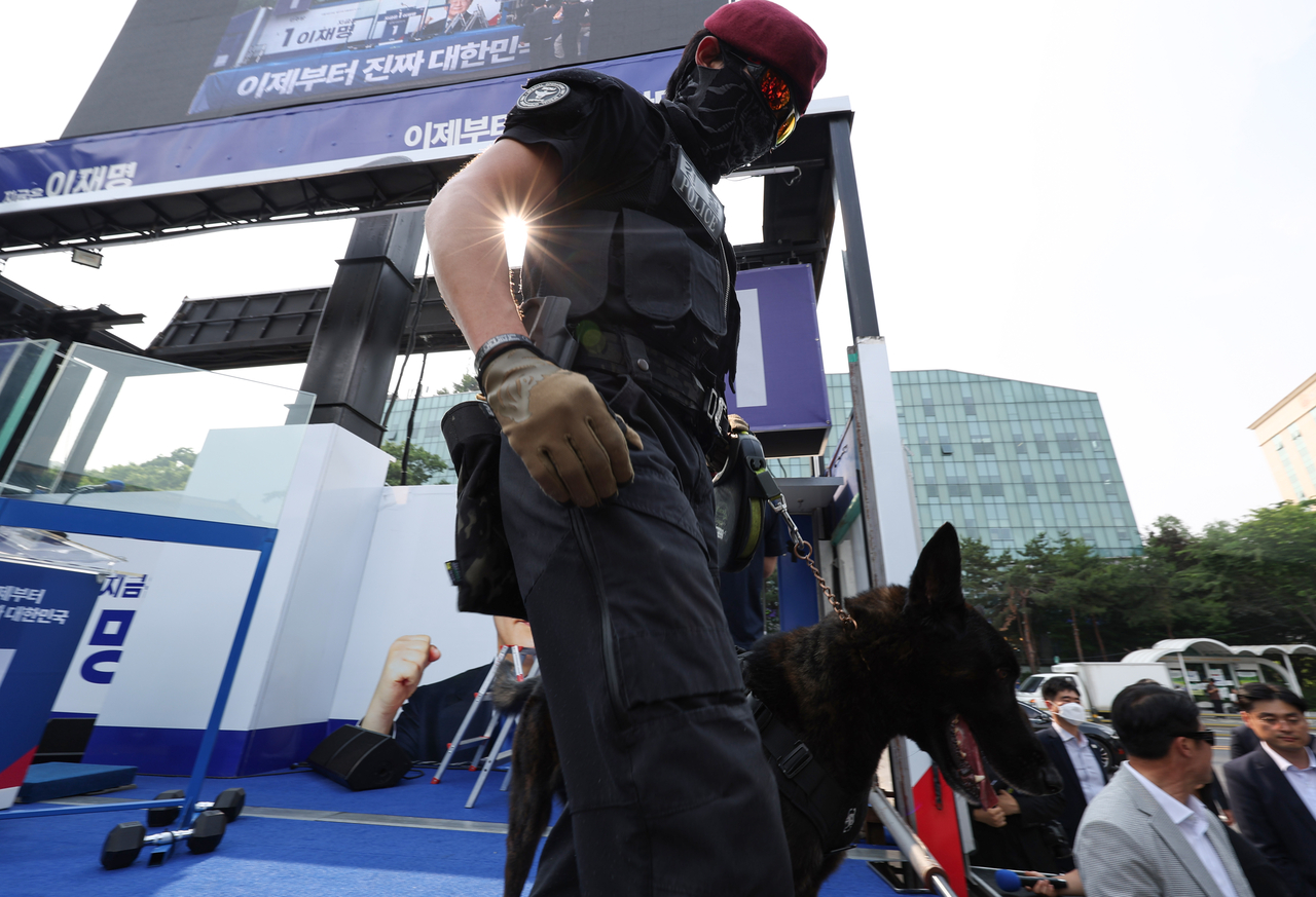 A police officer and a detection dog search for explosives at Democratic Party of Korea presidential candidate Lee Jae-myung's rally held at the main gate of Children's Grand Park in Gwangjin-gu, eastern Seoul on May 28. (Yonhap)