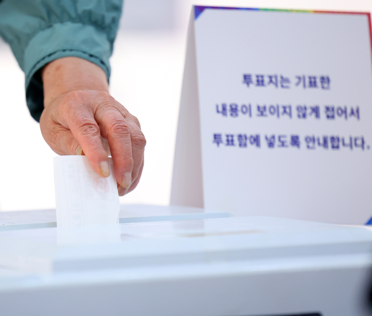 A voter places a ballot into the box at a polling station in Busan on Tuesday. (Yonhap)