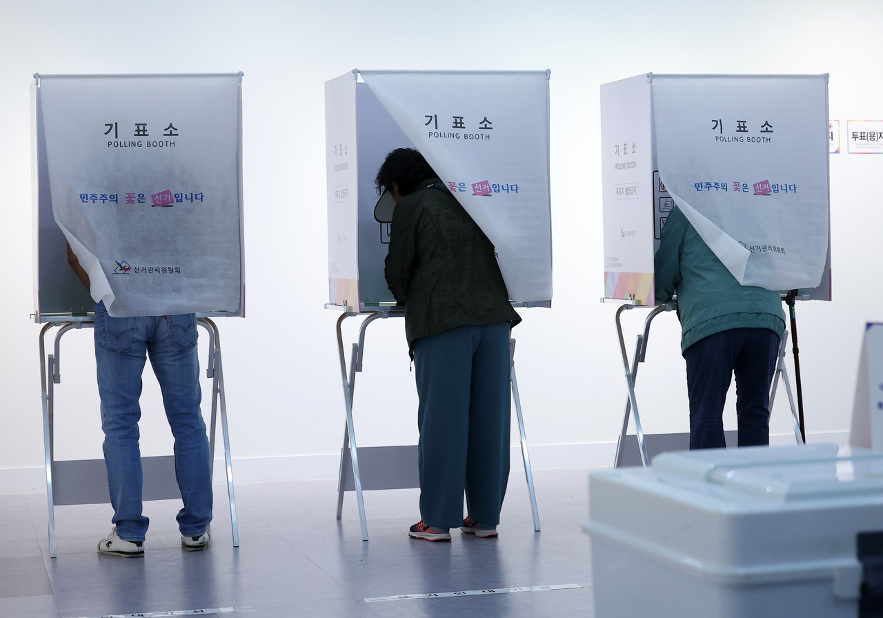 Voters cast their ballots at a polling station in Busan on Tuesday. (Yonhap)