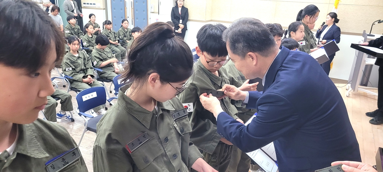 이동신 울릉교육장이  어린이 독도의용수비대원에게 명찰을 붙여주고 있다[울릉교육지원청 제공]