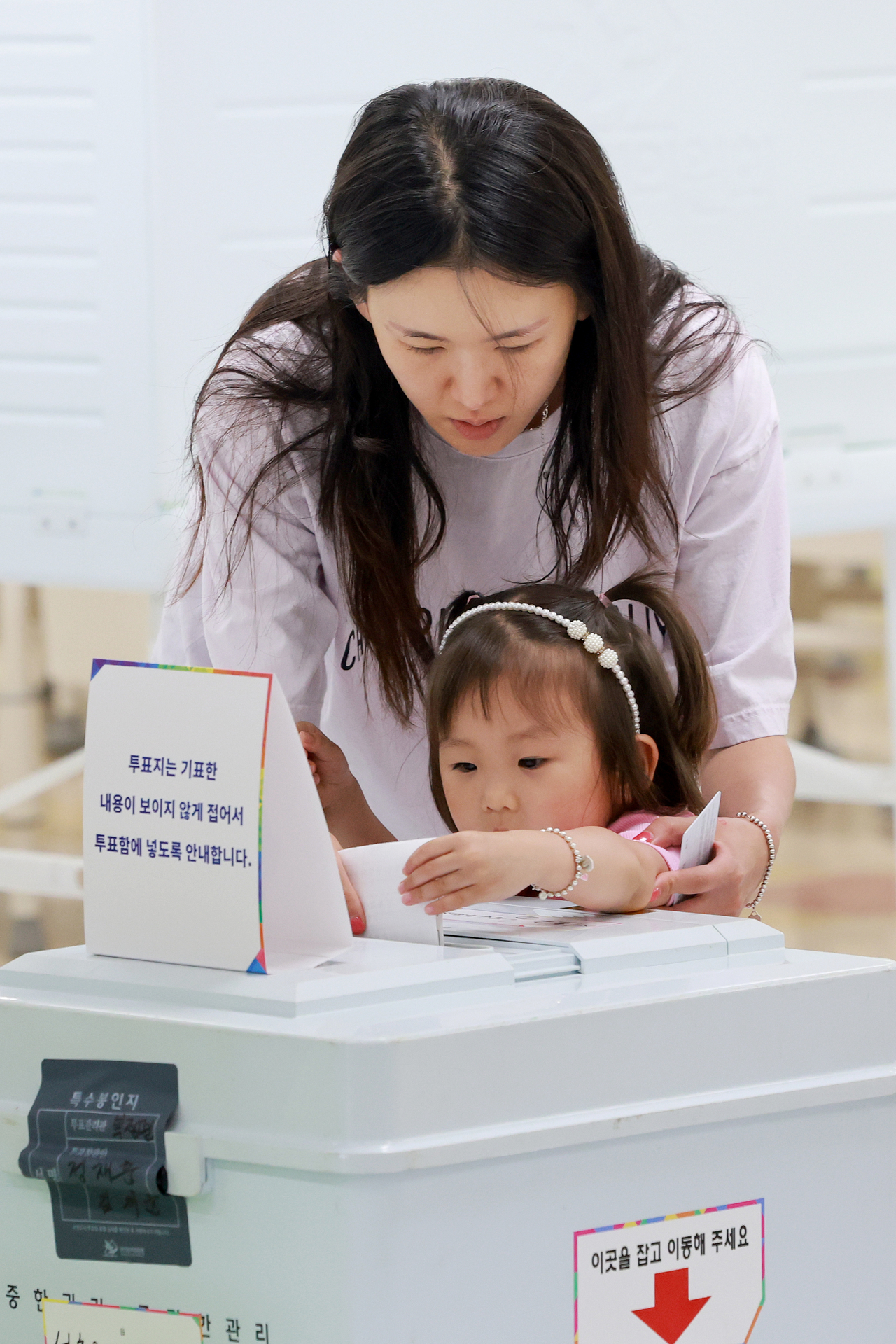A voter casts a ballot with a child on Tuesday at a polling station set up in Seocho-gu, Seoul. (Yonhap)