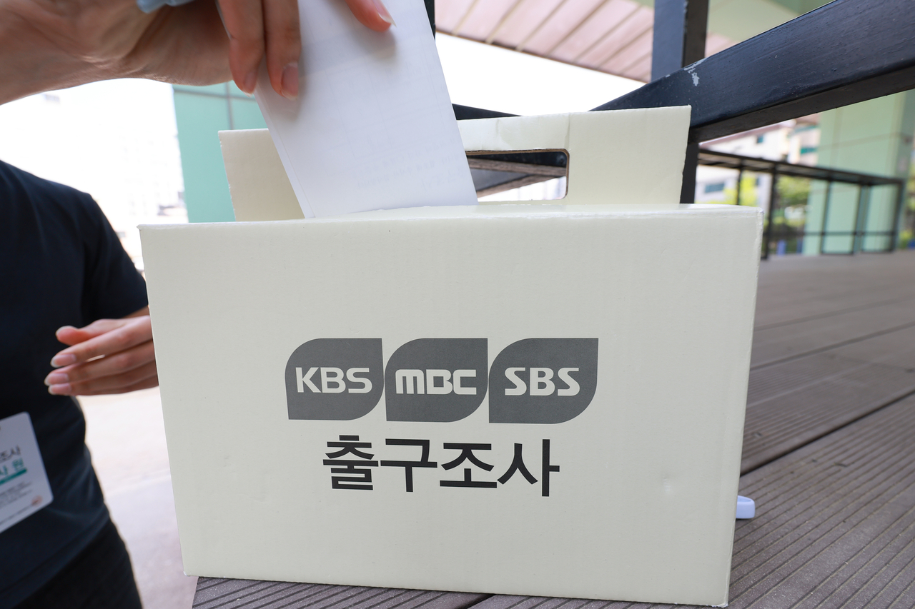 An exit poll respondent places a survey form into a collection box in front of the Seocho 3-dong No. 4 polling station set up at Seocho High School in Seocho-gu, Seoul, Tuesday. (Yonhap)