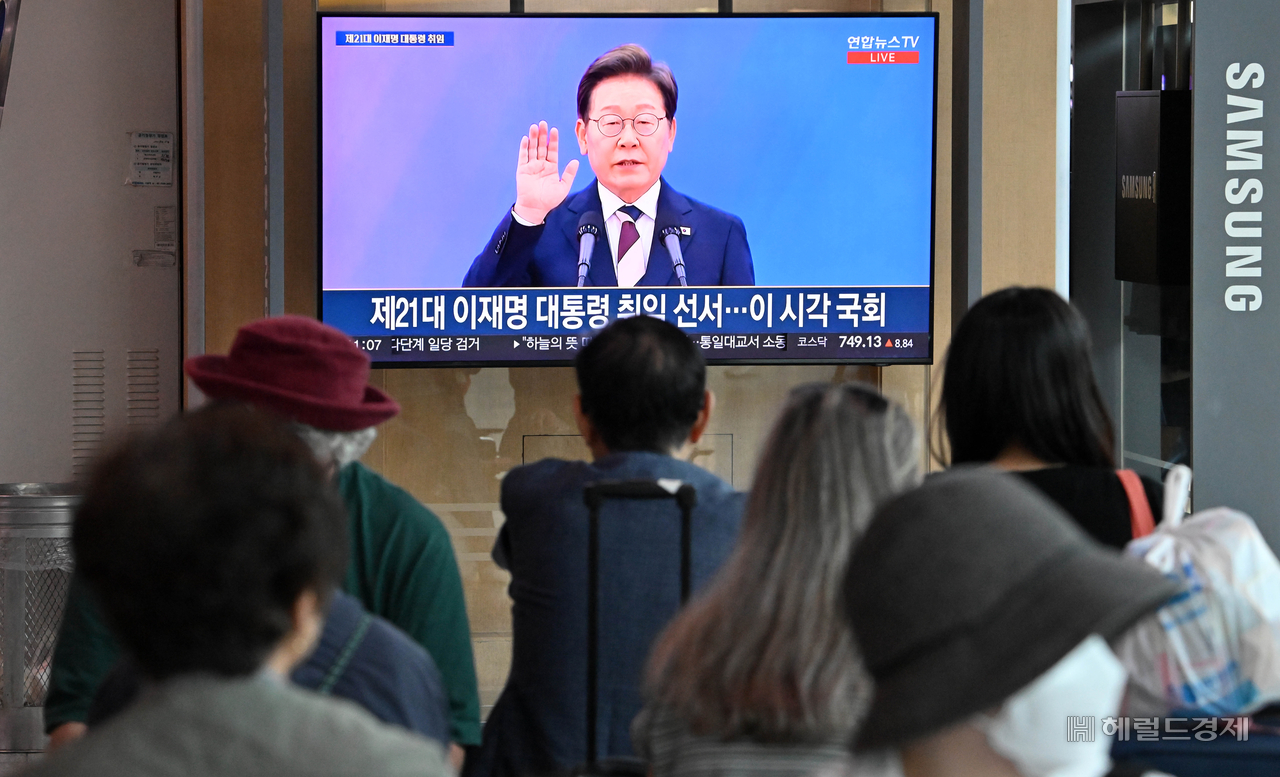 4일 오전 서울 용산구 서울역 대합실에서 시민들이 이재명 대통령 취임선서식 뉴스를 시청하고 있다.   임세준 기자