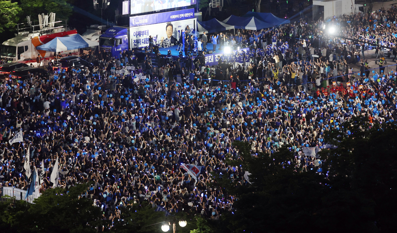 Democratic Party presidential candidate Lee Jae-myung greets a crowd of supporters with a cheering stick as he kicks off his final campaign rally at Yeouido Park in Seoul on Tuesday, a day before the election. (Yonhap)
