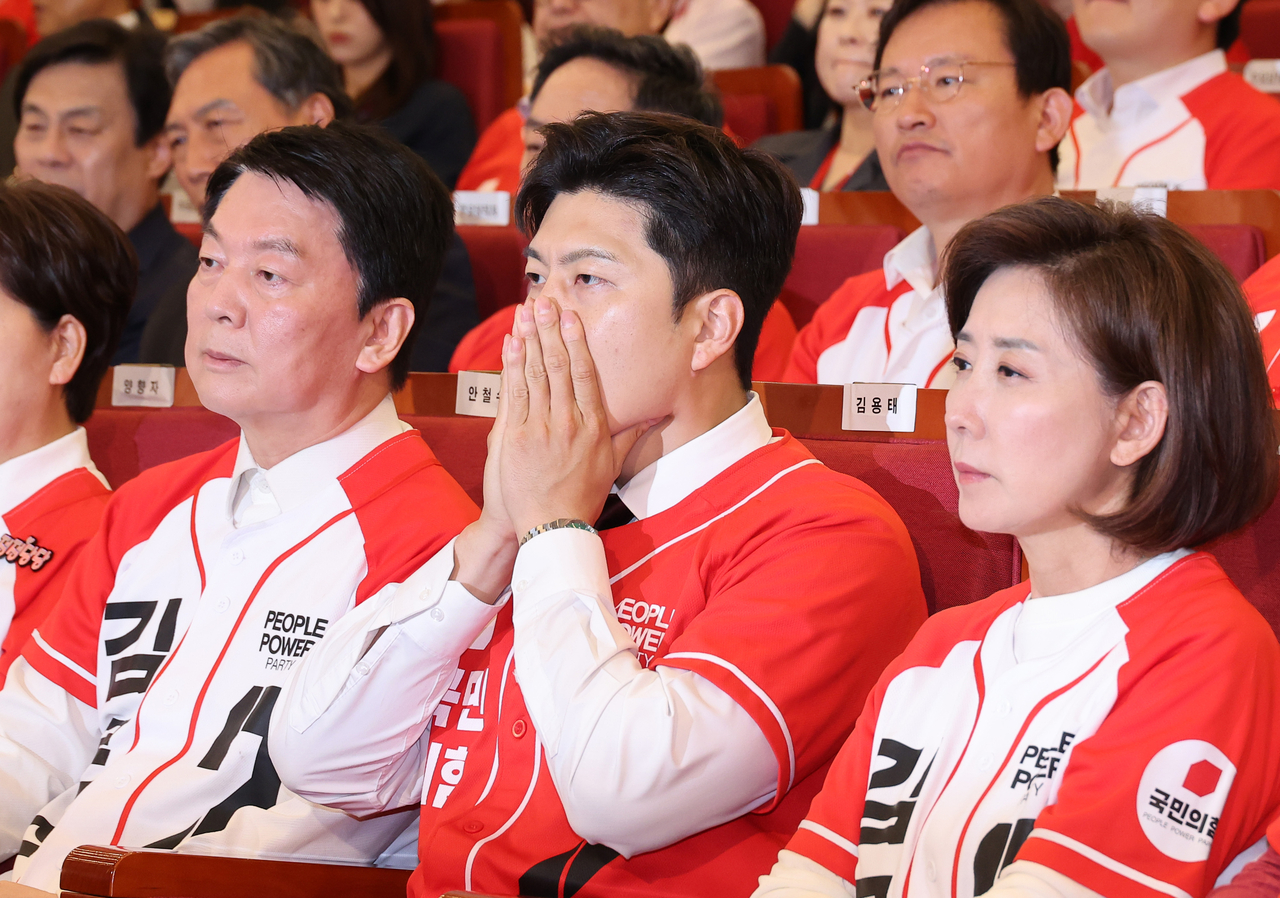 People Power Party interim leader Kim Yong-tae (center) covers his mouth with his hands as he watches the exit polls at the National Assembly Library, where their vote-counting command center was set up, on Tuesday. Yonhap