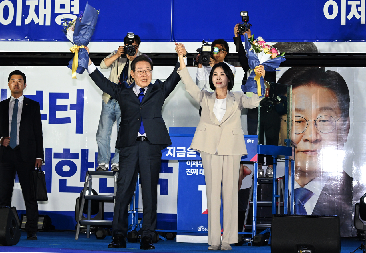 이재명 대통령이 4일 제21대 대통령 당선이 확실시 된 후 부인 김혜경 여사와 서울 여의도 국회 인근에서 당 주최로 열린 스포츠토토 베팅샵개표방송 행사에 참석해 시민들을 향해 두 팔을 들어 인사하고 있다. [공동취재, 연합]