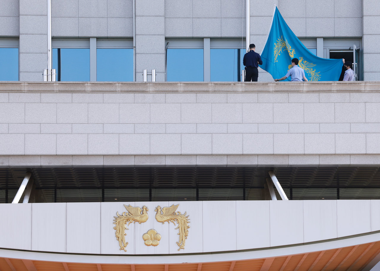 Three presidential officials raise a flag bearing the symbol of the South Korean presidency on the leftmost flagpole at the presidential office in Yongsan-gu, Seoul, Wednesday. (Yonhap)