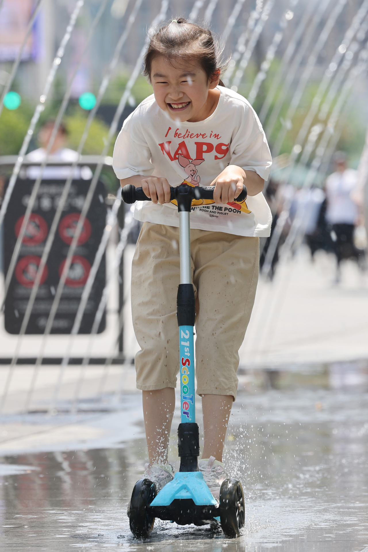 A child rides a scooter through the fountain tunnel. (Yonhap)