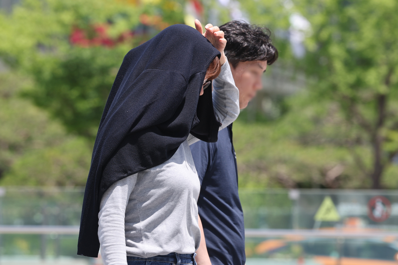 A pedestrian tries to escape the heat by covering her head with a jacket. (Yonhap)