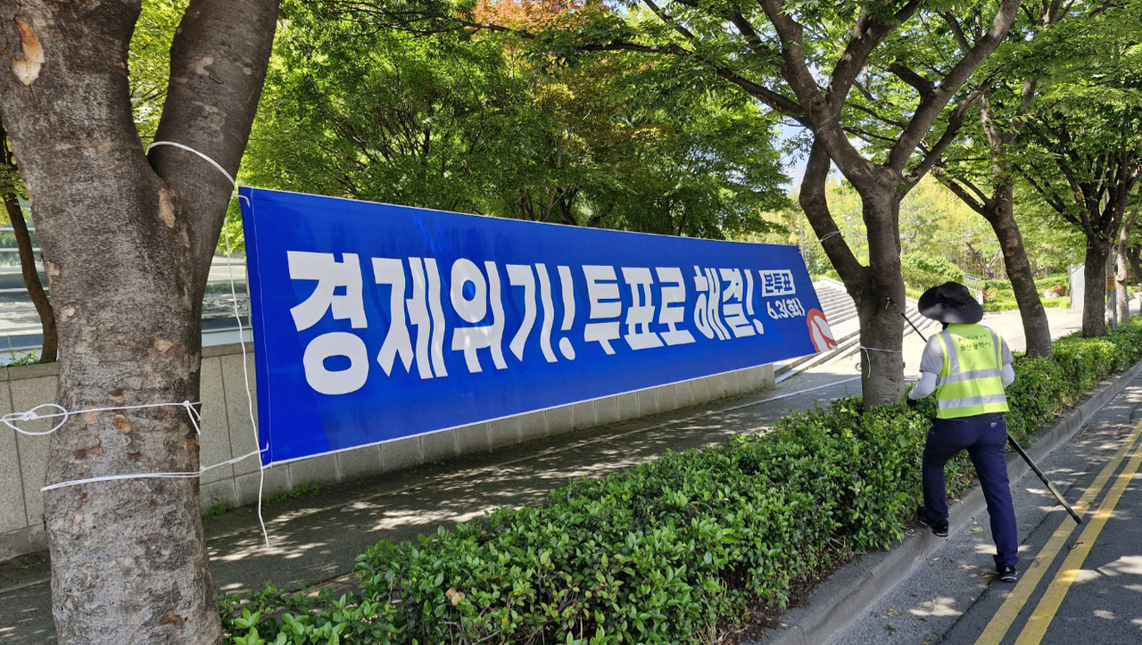 울산 시가지 도로가에 걸린, 제21대 대통령선거 투표를 독려하는 내용의 토토사이트 테이블을 정비반원이 철거하려 하고 있다.