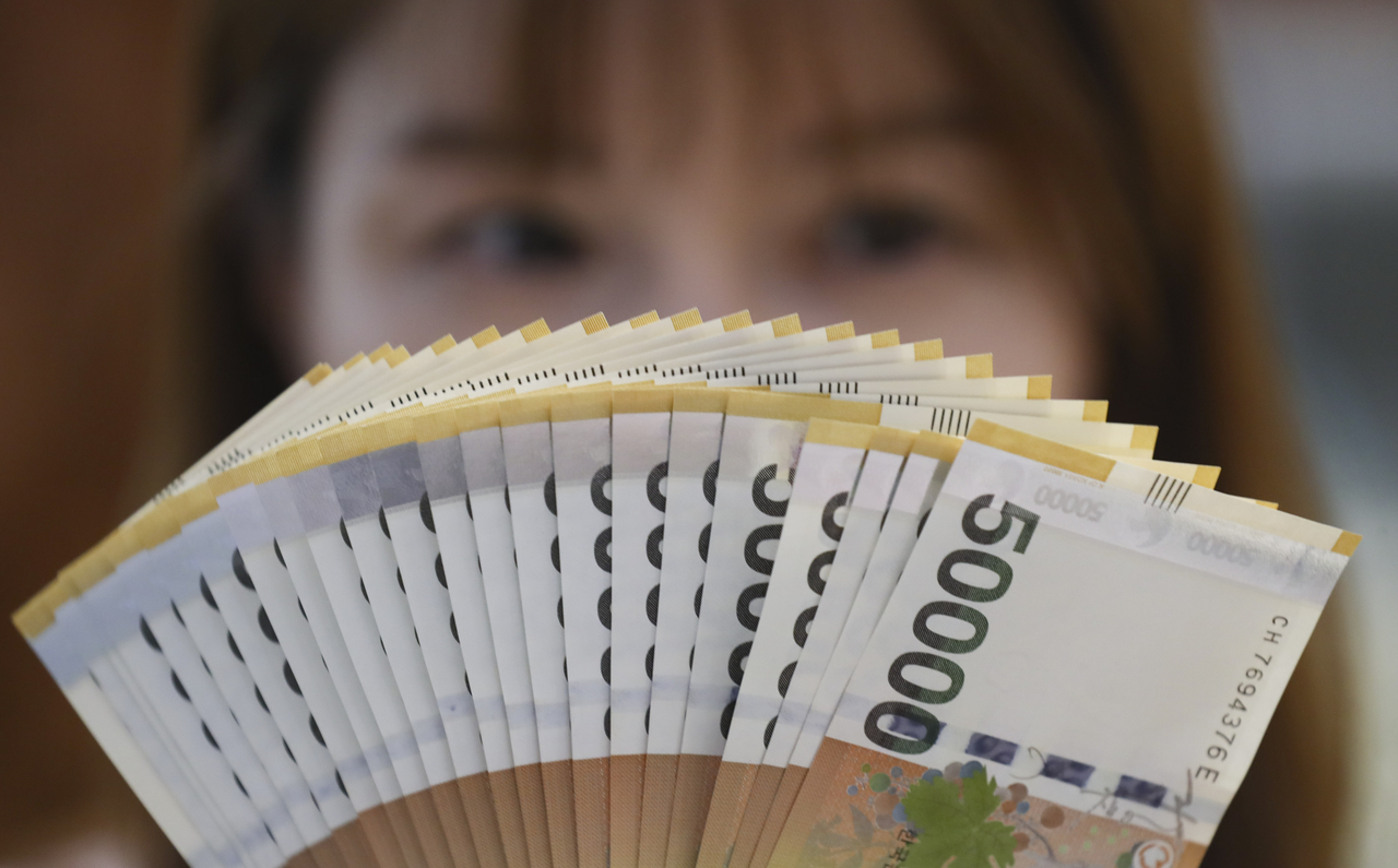 A Hana Bank official holds samples of 50,000 won-denominated bills in this 2023 file photo. (Newsis)