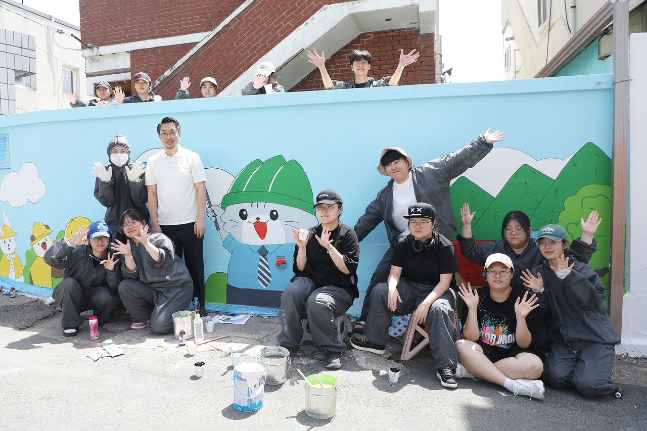 박재윤 학과장과 학생들이 벽화그리기를 마치고 기념사진을 촬영하고 있다.[영남이공대 제공]