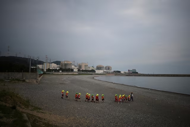 Children visit a seashore as Wolseong Nuclear Power Plant is seen in the background at Naa-ri village in Gyeongju, South Korea, August 23, 2022. REUTERS/Kim Hong-Ji/File Photo Purchase Licensing Right