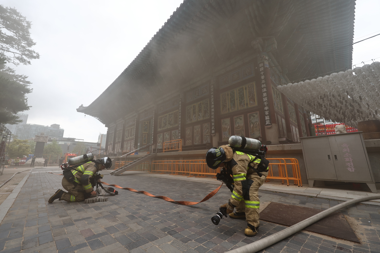 Firefighters work to extinguish a blaze at the Central Buddhist Museum next to Jogyesa Temple in Seoul on Tuesday.