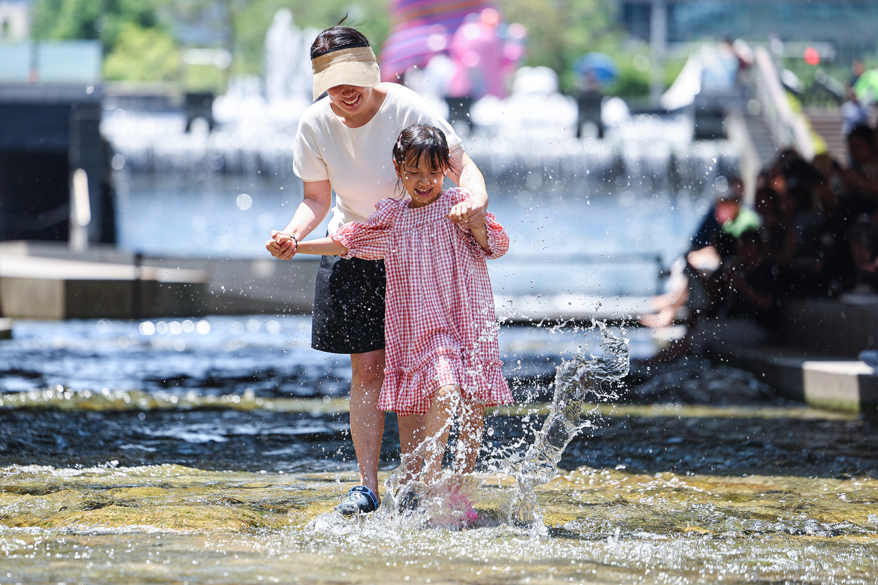 A mother and her child enjoy the water at Cheonggyecheon in central Seoul on Wednesday. (Yonhap)