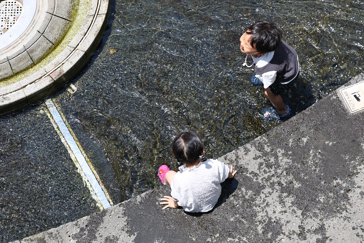 Two children play in the water at Cheonggyecheon in central Seoul on Wednesday. (Yonhap)