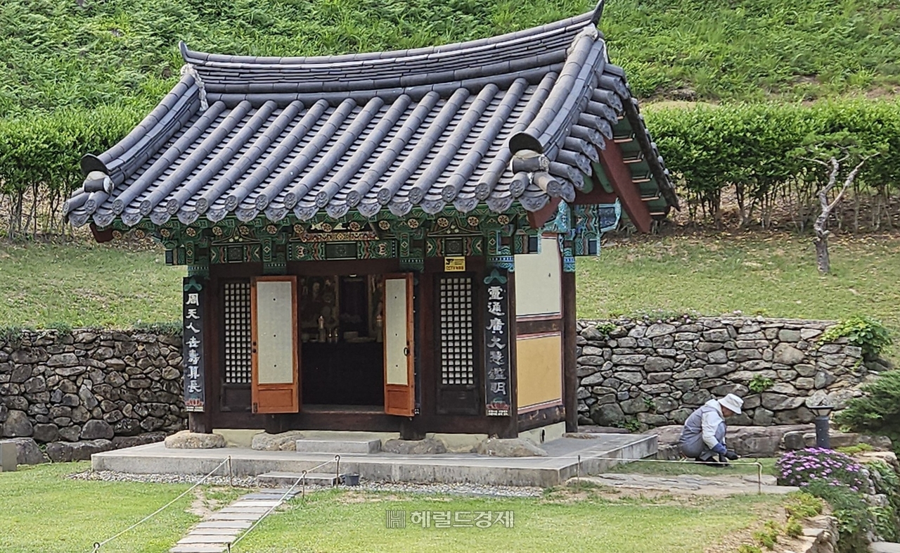 토토사이트 라운더스 삼성각 앞 잔디마당의 잡풀을 제거하는 여경 주지 스님 모습.