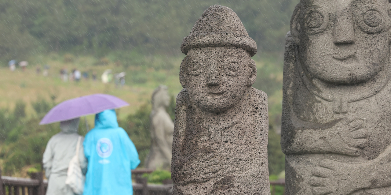 Wearing raincoats and sharing an umbrella, two tourists walk along a trail on Songaksan in Seogwipo, Jeju Island, Wednesday. (Yonhap)