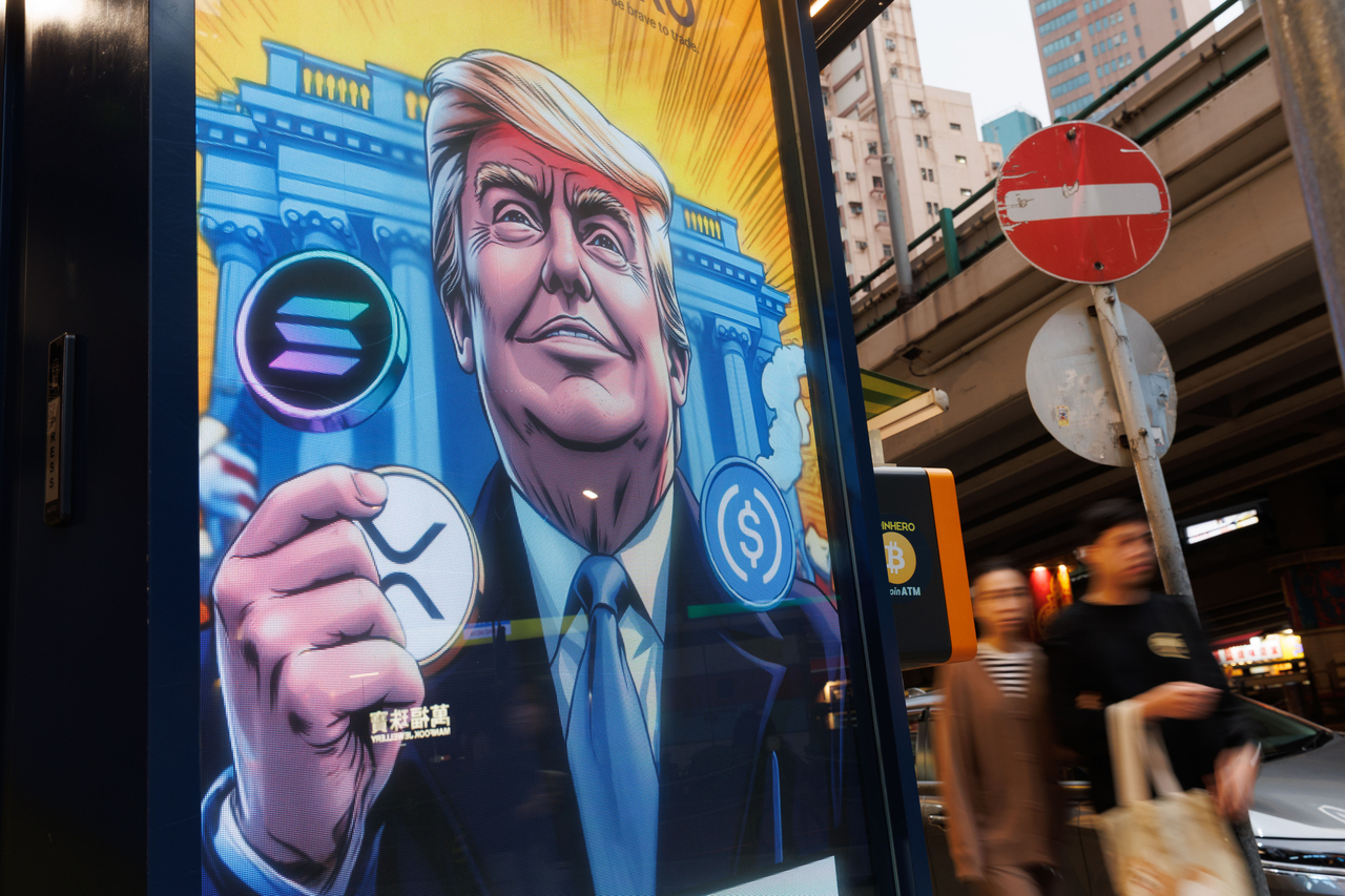 도널드 트럼프 미국 대통령이 솔라나, XRP, USDC 등 가상자산을 들고 있는 광고판 앞을 홍콩 시민들이 지나가고 있다.  [게티 이미지]