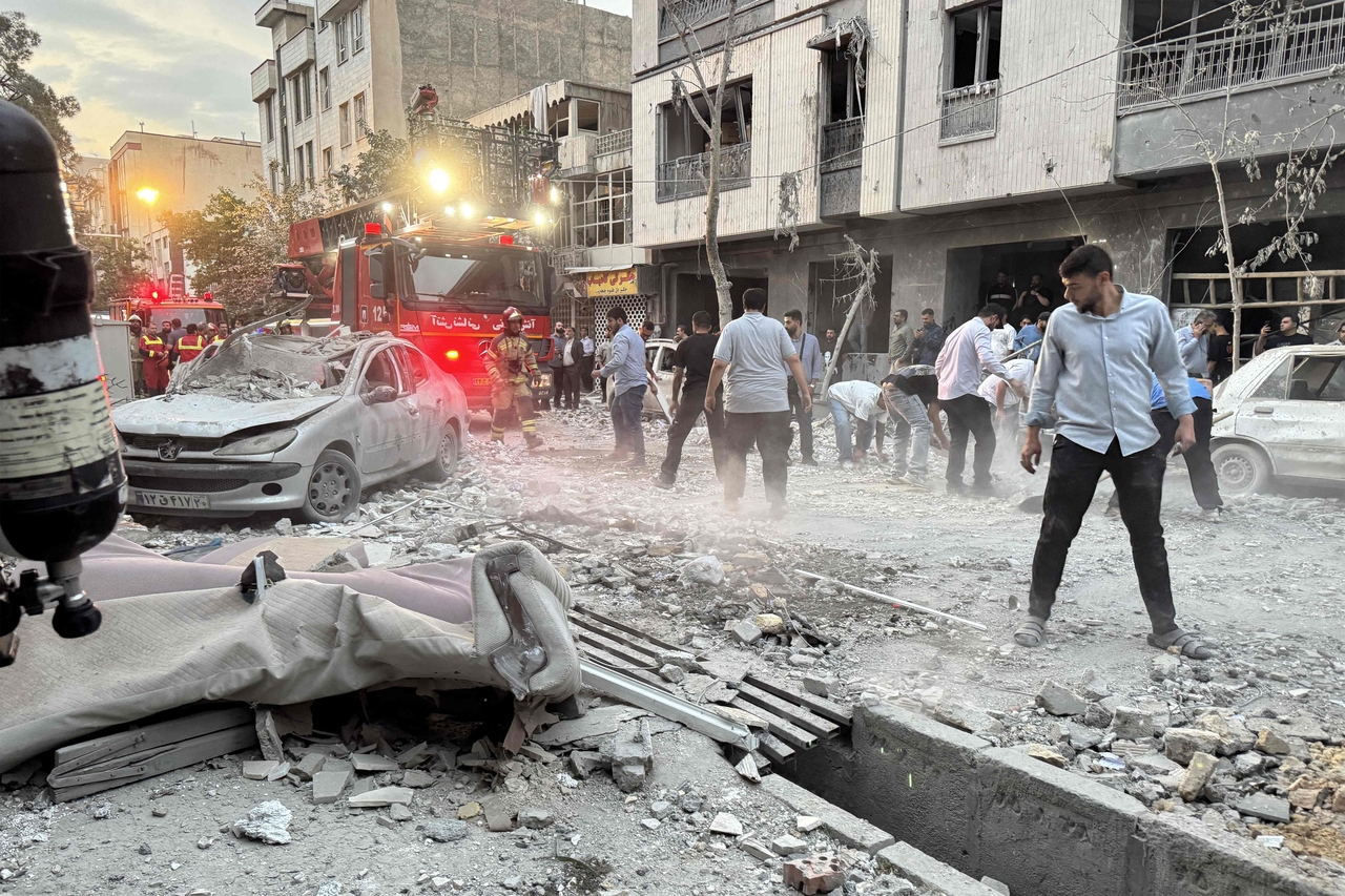 People and first-responders gather outside a that was hit by an Israeli strike in Tehran on Friday. Israel hit about 100 targets in Iran on Friday, including nuclear facilities and military command centres and killing senior figures including the armed forces chief and top nuclear scientists. (AFP)