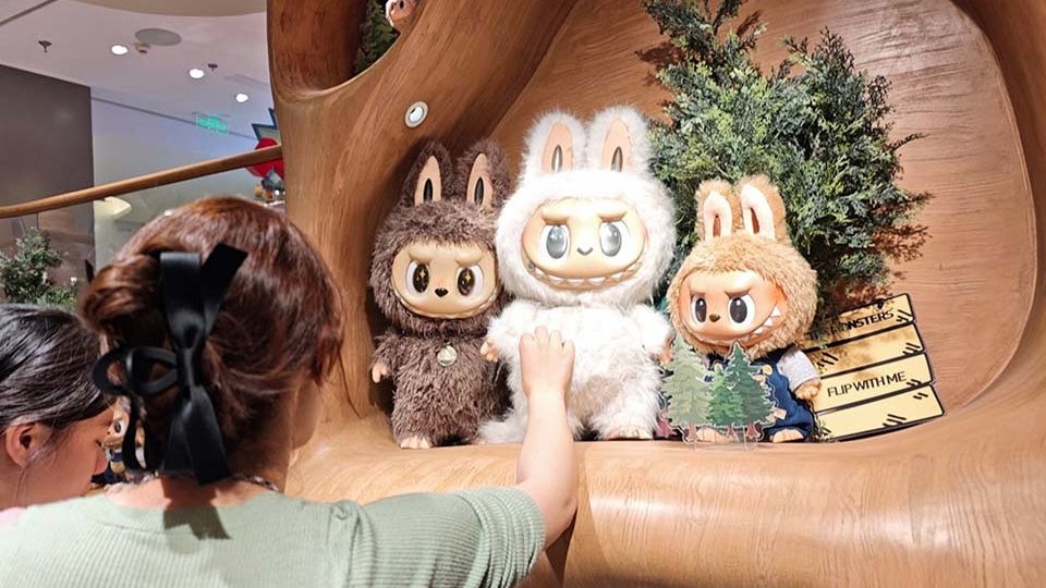 A customer looks at Labubu figures at a Pop Mart store in Shanghai.    (China Daily)