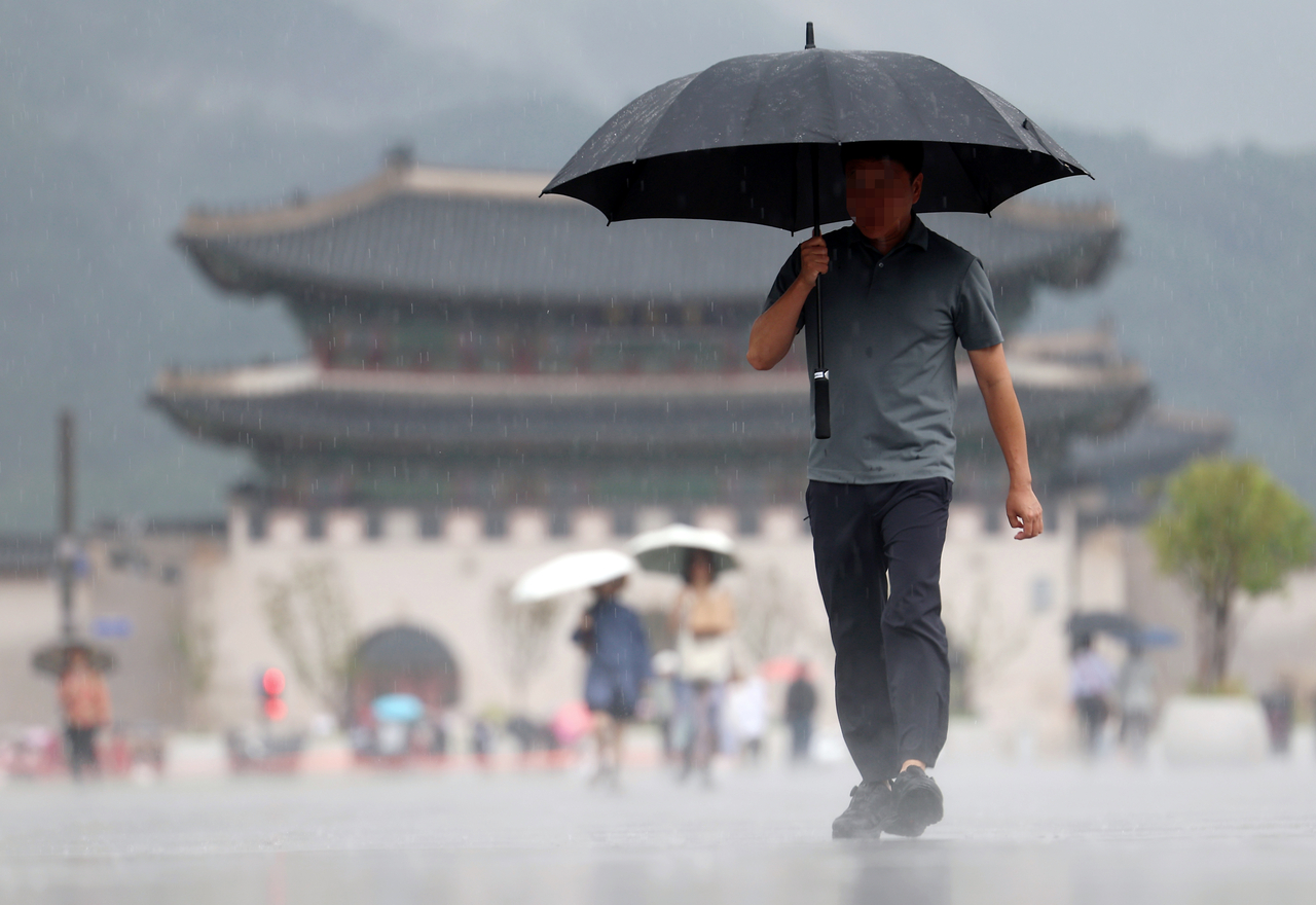 A pedestrian walks with an umbrella in Gwanghwamun Square in Jongno-gu, central Seoul, Monday. (Yonhap)