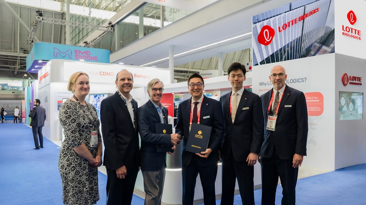 Lotte Biologics CEO James Park (third from right), Head of Global Strategy Shin Yoo-yeol (second from right) and Head of Global PMO Brett Budis (second from left) pose for a photo with Ottimo Vice President Joseph Shultz (third from left) following the signing of a contract agreement, in front of the Lotte Biologics booth at BIO USA 2025 on Tuesday. (Lotte Biologics)