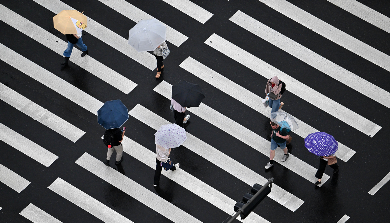 People shield themselves with umbrellas during the monsoon rain in Seoul on Friday. (Im Se-jun/The Korea Herald)