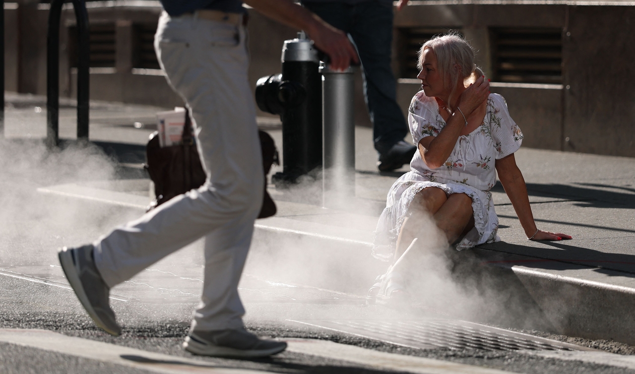 A tourist poses for pictures in steam grate on Wall Street in New York, Monday. (AFP-Yonhap)