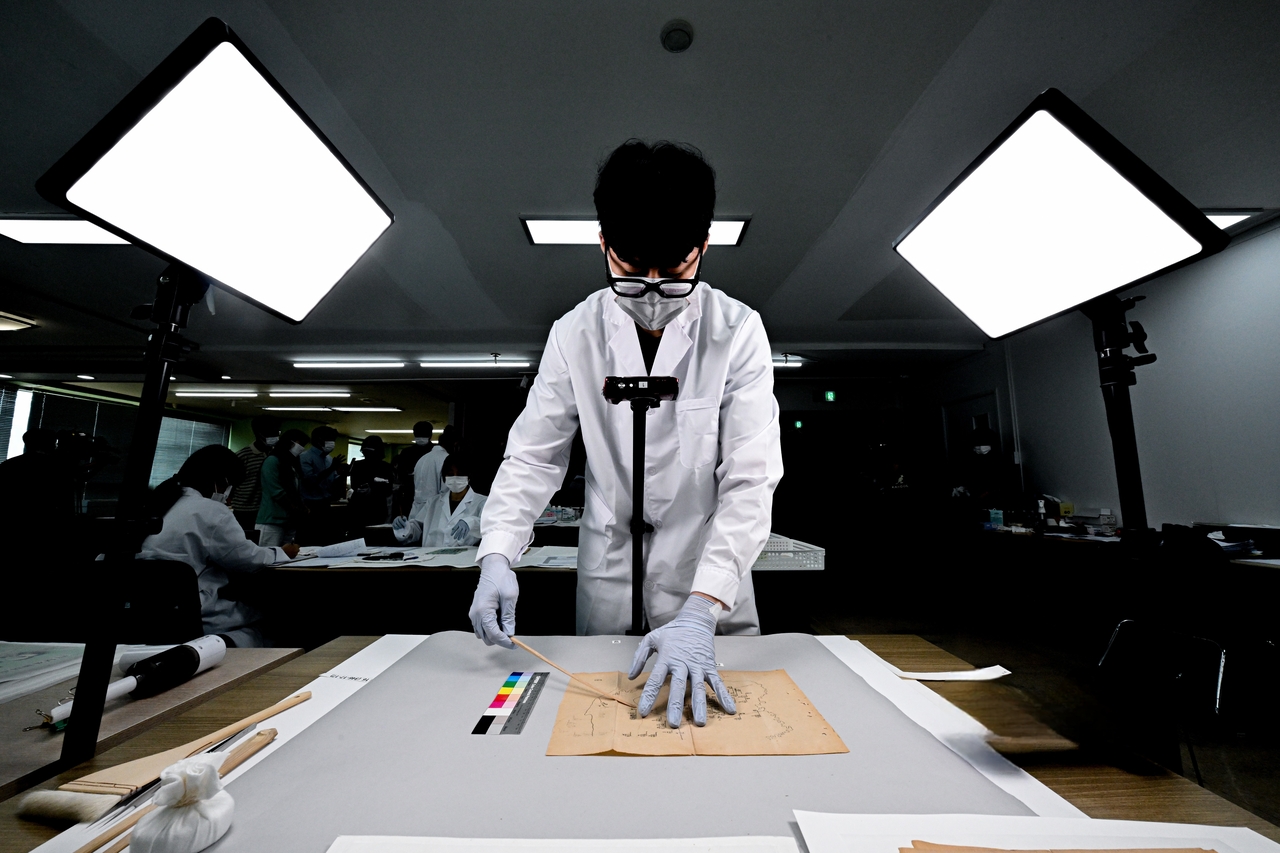 A restoration specialist photographs a document and measures its color value at the Army Archives Management Group's preservation site in Gyeryong, South Chungcheong Province, Monday. (Republic of Korea Army)