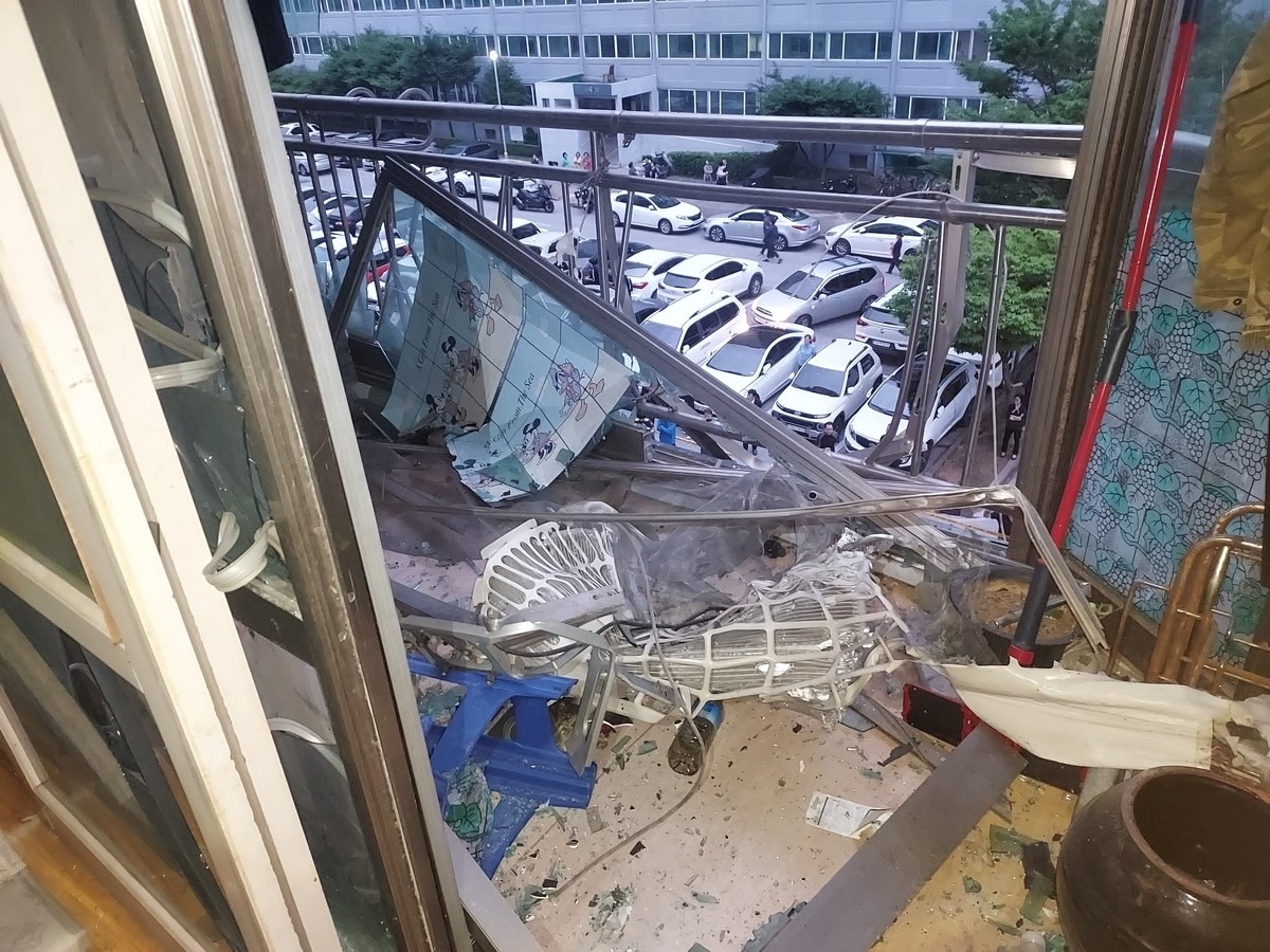 The view from inside the damaged apartment shows broken windows and bent railings caused by the force of the blast. (Jeonbuk Fire Service)