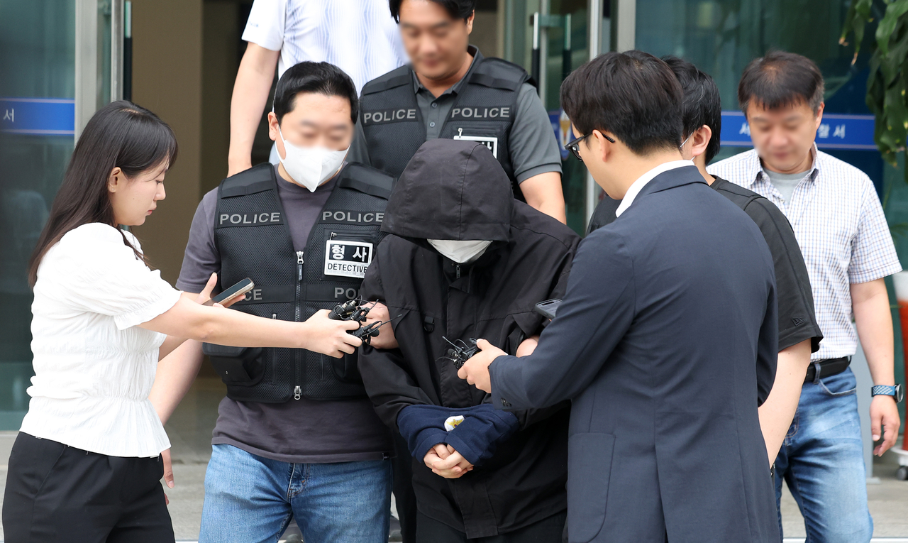 A suspect accused of posting multiple threats of attacks against elementary students and random women is being transferred from Jungnang Police Station in Seoul to the prosecution on Thursday. (Newsis)