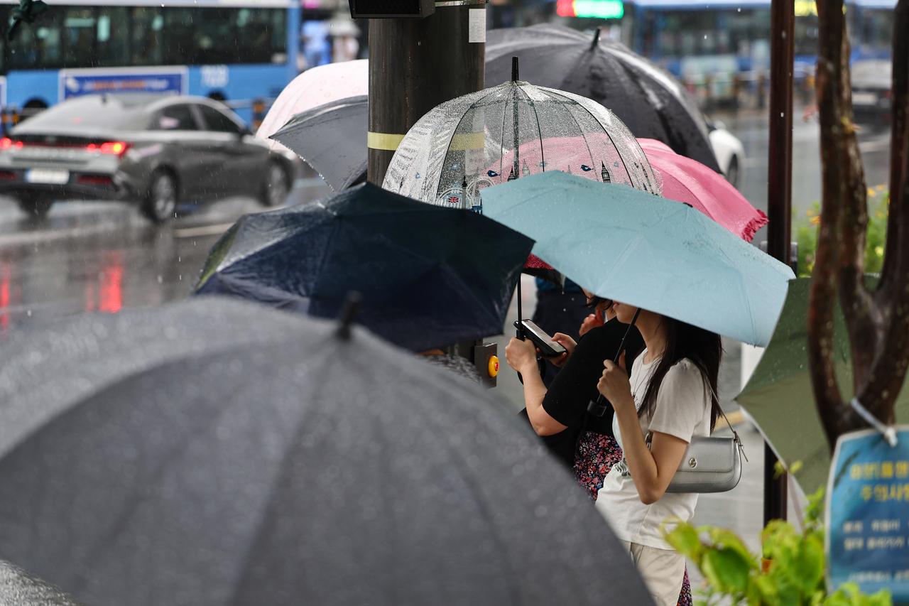 서울 전역에 호우주의보가 내린 지난 20일 서울 종로구 광화문 네거리에서 우산을 쓴 시민들이 신호를 기다리고 있다. [연합]