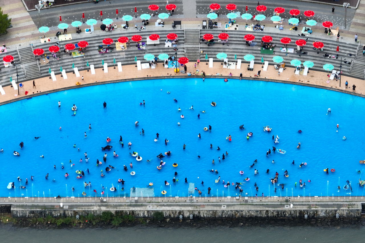 People beat the heat by resting under parasols or swimming at Nanji Hangang Park in Mapo-gu, Seoul, on Sunday. (Yonhap)