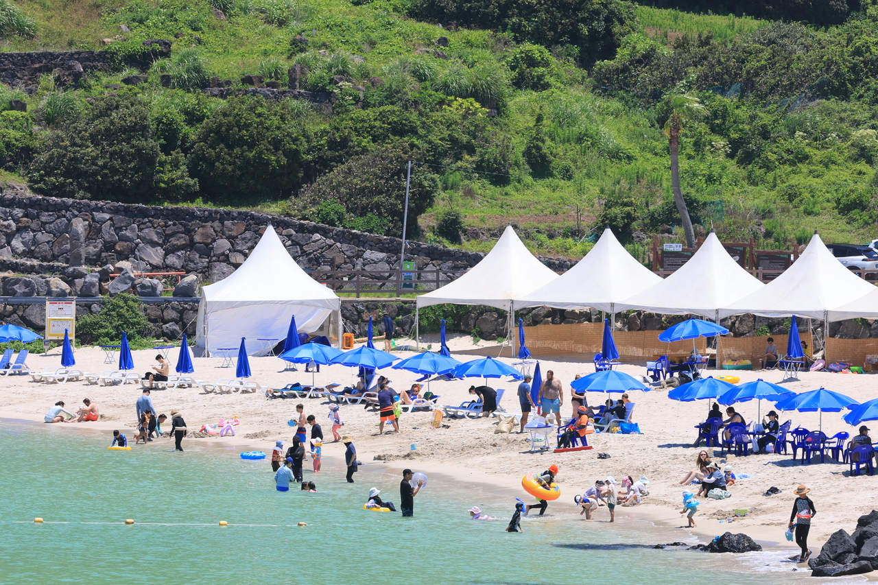 People enjoy the summer at Hamdeok Beach in Jocheon-eup, Jeju Island, on Sunday, as a heat wave warning was issued for the island’s eastern region. (Yonhap)