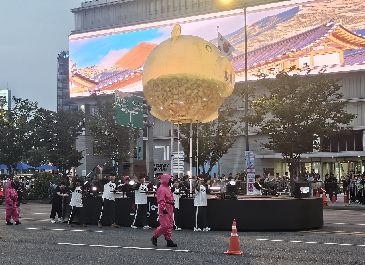 The piggy bank from "Squid Game" is paraded down Sejong-daero during Saturday’s celebration marking the series finale. (Lee Yoon-seo/The Korea Herald)