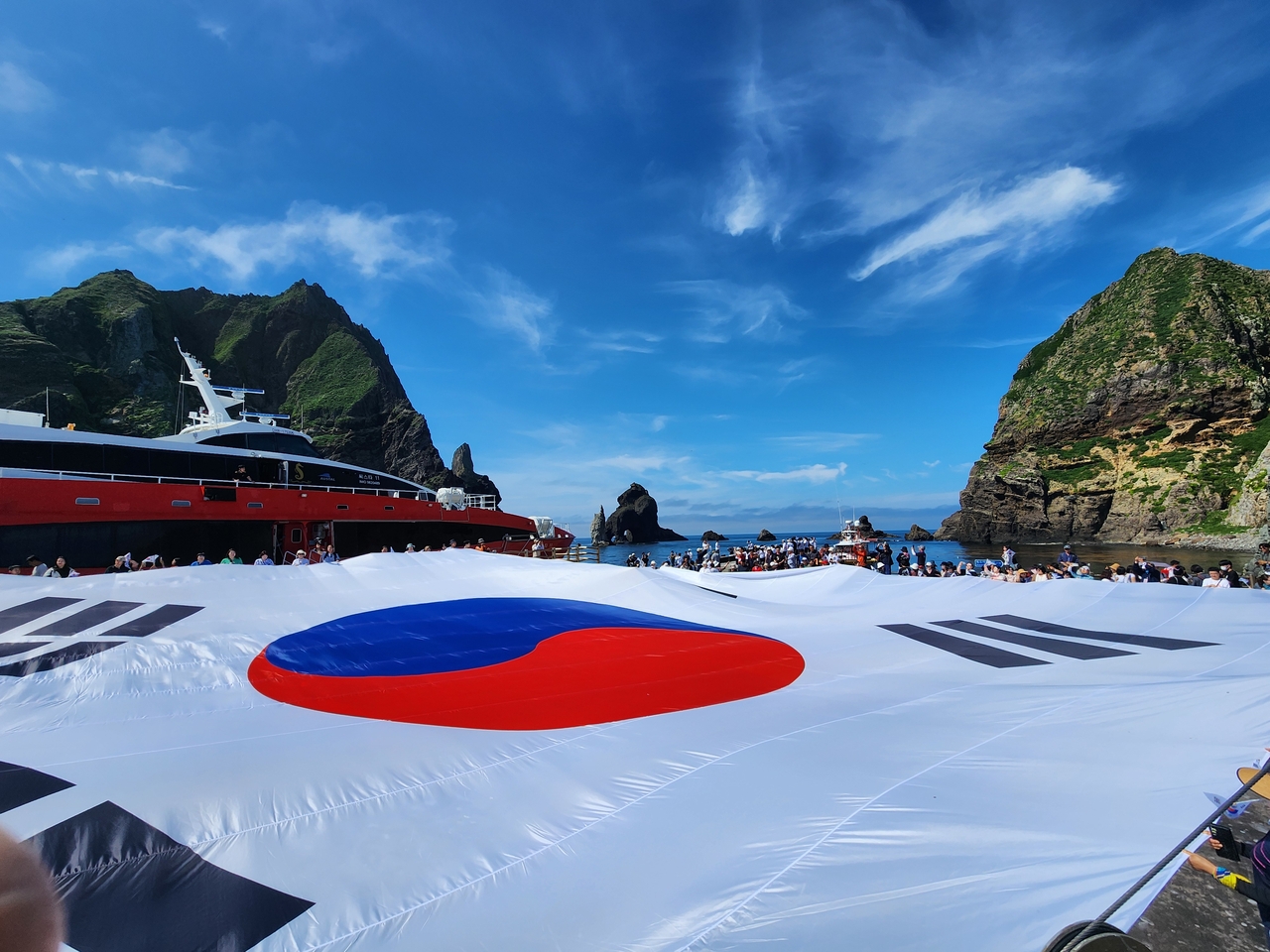 광복 80주년을 맞아 지난 28일 시민 80명이 독도 동도 선착장에서 가로 30m, 세로 20m 크기의 초대형 태극기를 펼치고 있다. [서경덕 교수 제공]