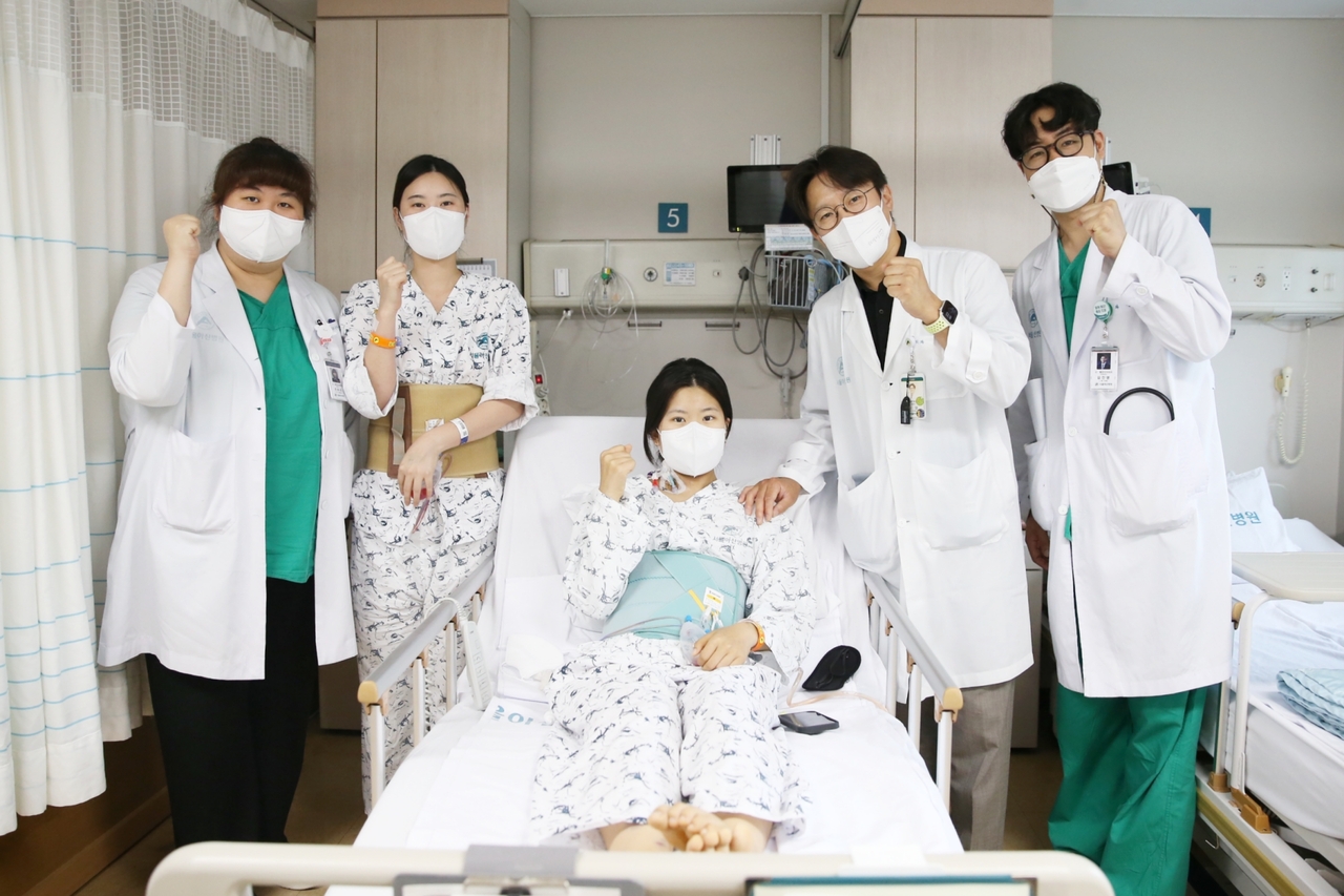 다낭성 신증후군으로 만성 신부전을 앓던 이가영 씨(가운데)가 로봇 원탑토토 후 순조롭게 회복하며 20일(금) 의료진과 기념사진을 찍고 있다. 왼쪽에서 두 번째가 공여자인 언니 이 모 씨, 네 번째가 수술을 집도한 서울아산병원 신·췌장이식외과 신성 교수