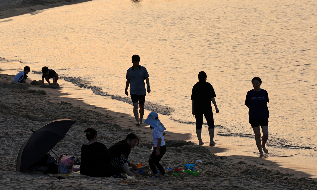 People enjoy the ocean breeze at Anmok Beach in Gangneung, a coastal city in Gangwon Province that experienced a tropical night on Sunday. (Yonhap)